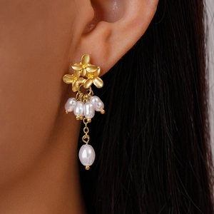 Vue détaillée de boucles d'oreilles fleur dorées avec de élégants glands de perle