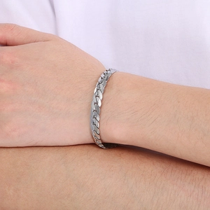 Close-up of silver Cuban link chain bracelet with engraved floral patterns on wrist