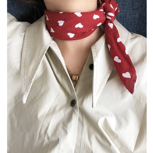 Close-up of red cotton linen neck scarf with white heart patterns on a model