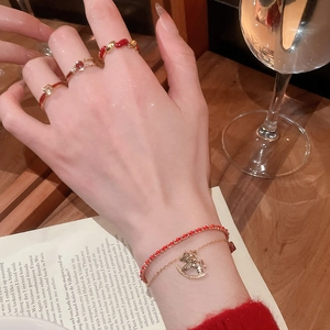 Macro detail of gold plated rings and red horse charm bracelet on hand with books
