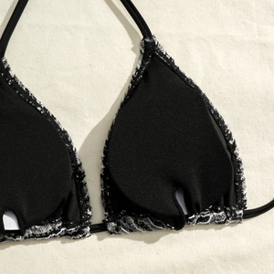 Detail shot of halter bikini top interior with XS size label and black fabric texture