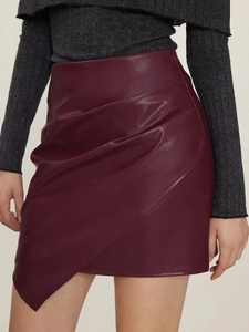 Détail de la jupe en similicuir bordeaux avec coupe asymétrique et fronces à la taille