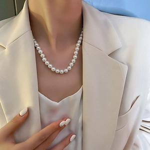 Elegante collana di perle barocche indossata da una modella in abito beige in stile francese