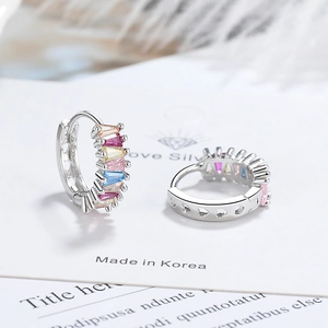Macro detail of silver hoop earrings with colorful zircon and heart-shaped hollow patterns