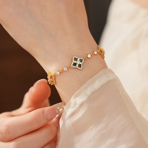 Gros plan d'un bracelet trèfle doré avec pierres vertes et zircons au poignet d'une femme