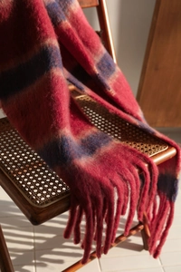 Detailed texture of thick tassel fringe on a red and blue striped plaid scarf