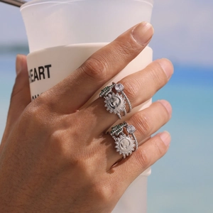 Silver sunburst ring with green zircon stones on hand against beach background