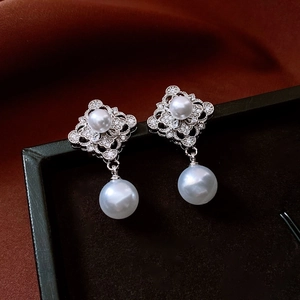 Macro shot of silver hollow diamond earrings with dangling white pearls and rhinestones