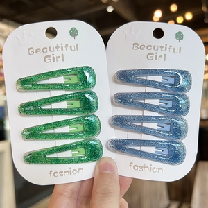 Close-up of glitter resin drop hair clips in sparkling blue and green for girls