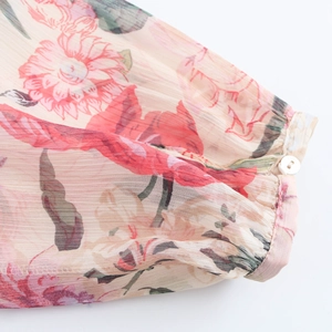 Close-up of floral chiffon dress cuff with a pink base and delicate white button detail
