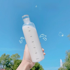Close-up of clear water bottle with black time markers held against a bright blue sky