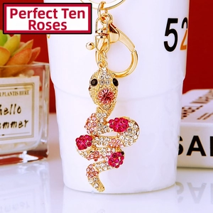 Close-up of luxury snake keychain with pink rhinestones on a white porcelain cup
