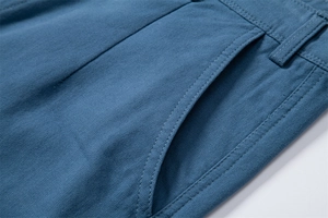 Macro detail of high-density cotton twill fabric and reinforced stitching on blue cargo shorts