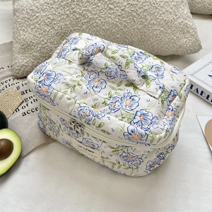 Detailed view of blue floral quilted cosmetic bag with dual zippers and sturdy top handle