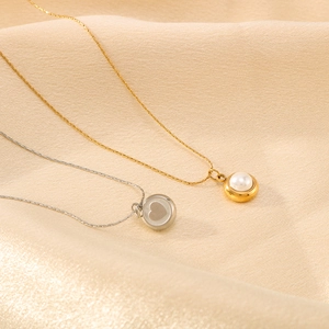 Gold and silver stainless steel pearl necklaces with heart pendant on beige silk fabric