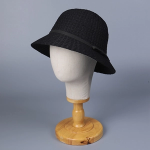 Elegant black knit straw bucket hat with silk bow ribbon on display mannequin