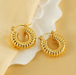 Detail of gold croissant hoop earrings with spiral texture on silk background