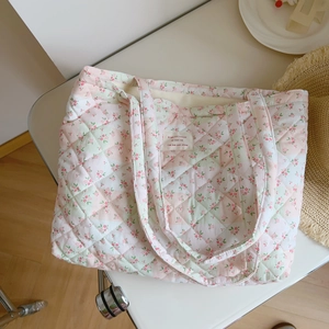 Close-up of pink floral quilted cotton tote bag with French label on a white chair