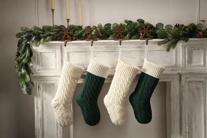 Detail of four knit Christmas stockings in ivory and dark green with cable knit pattern