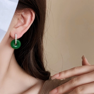 Gros plan d'une boucle d'oreille jade donut avec accents de diamants sur un mannequin