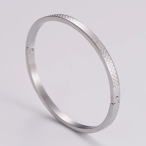 Macro view of silver stainless steel bangle featuring a precise checkered pattern engraving
