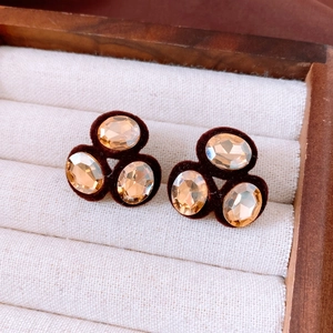 Detail shot of vintage oval champagne crystal earrings with brown velvet base on wood