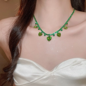 Detail view of a luxury gold necklace with green heart pendants and sparkling zircons
