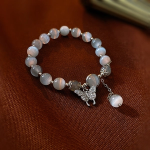 Detail of beaded bracelet with synthetic cat's eye stone and silver butterfly pendant