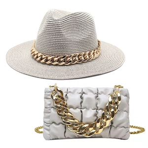 Detail of beige straw fedora and quilted crossbody bag with thick gold acrylic chains