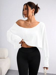 Detail of off-shoulder white crop top with long sleeves and elegant draped fabric