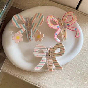 Close-up of three colorful resin bow hair claws with stripes, polka dots, and hearts