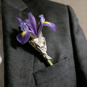 Detailaufnahme der silbernen Blumenstrauß-Brosche am Revers eines schwarzen Anzugs
