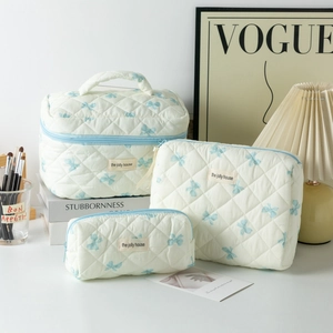Three-piece quilted cosmetic bag set with blue bow pattern and top handle design