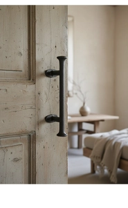 Gros plan sur une poignée de porte en fonte noire mate avec texture sablée sur porte en bois