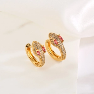Macro detail of gold snake hoop earrings featuring red gemstone eyes and cubic zirconia