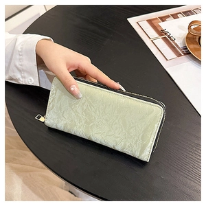 Detail of mint green crushed velvet long wallet with secure gold zipper closure