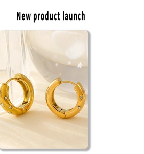 Close-up of gold starburst engraved hoop earrings with micro-inlaid crystals