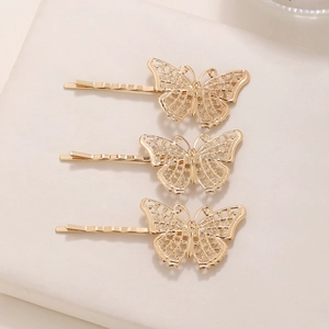 Three gold minimalist hollow butterfly metal hair clips displayed on a beige base