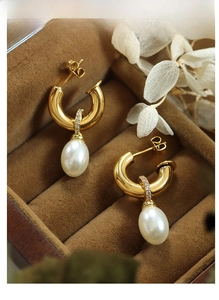 Detailed view of Baroque pearl C-shape earrings with zircon studs in a luxury jewelry box
