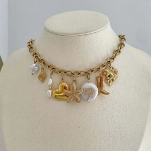 Detail of gold chain necklace with pearl, starfish, heart, and boot pendants on a bust