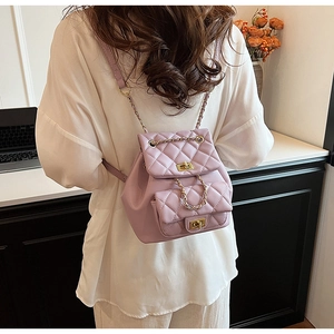 Rear view of a lavender quilted backpack with gold chains on a woman in a white shirt