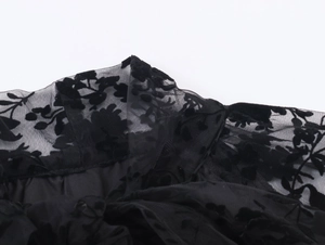 Detail of sheer black mesh fabric with elegant flocked floral patterns and velvet texture