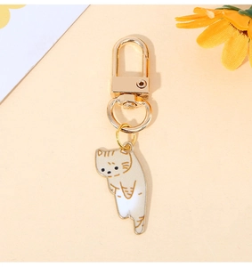 Close-up of a cute orange and white enamel cat charm with a golden lobster clasp