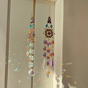 Detail of sun and moon crystal suncatchers casting rainbow light on a neutral background