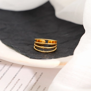 Detailed macro shot of a four-layer gold beaded texture open ring on dark background