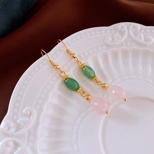Detail of drop earrings with green and pink beads on white embossed ceramic plate