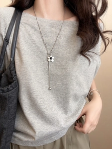 Detail showing a silver flower necklace with black center and long Y-shaped tassel