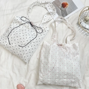 Detail of fabric tote bags with heart patterns and decorative bow tie closures
