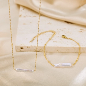 Elegant gold necklace and bracelet set with baroque freshwater pearls on silk background