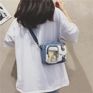 Detail view of small canvas crossbody bag with blue contrast pockets and adjustable strap